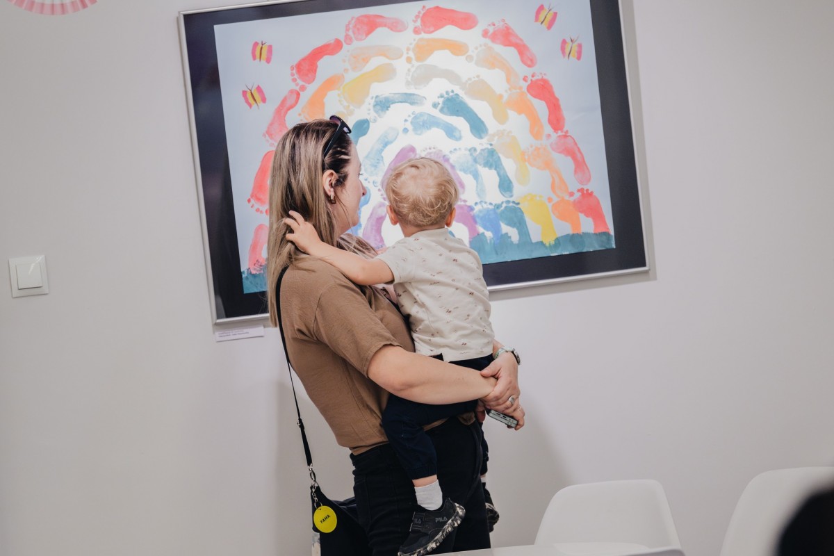 kobieta trzyma na rękach dziecko i patrzy na prace