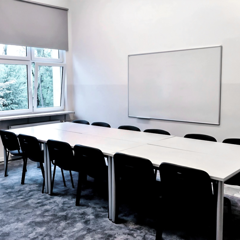 Sala ze stolikami, krzesłami i tablicą