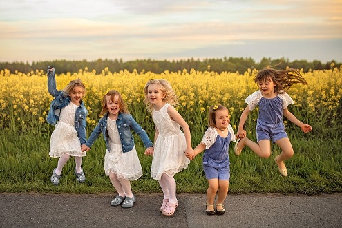 Zdjęcie przedstawia pięć dziewczynek, które skaczą na tle pola